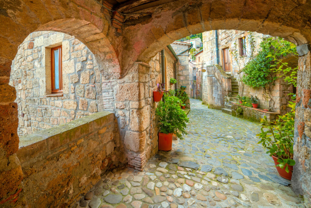 Narrow street in Medieval town Sorano  with old tradition buildings and flowers. Old small town in the Province of Grosseto, Tuscany (Toscana), Italy, Europe