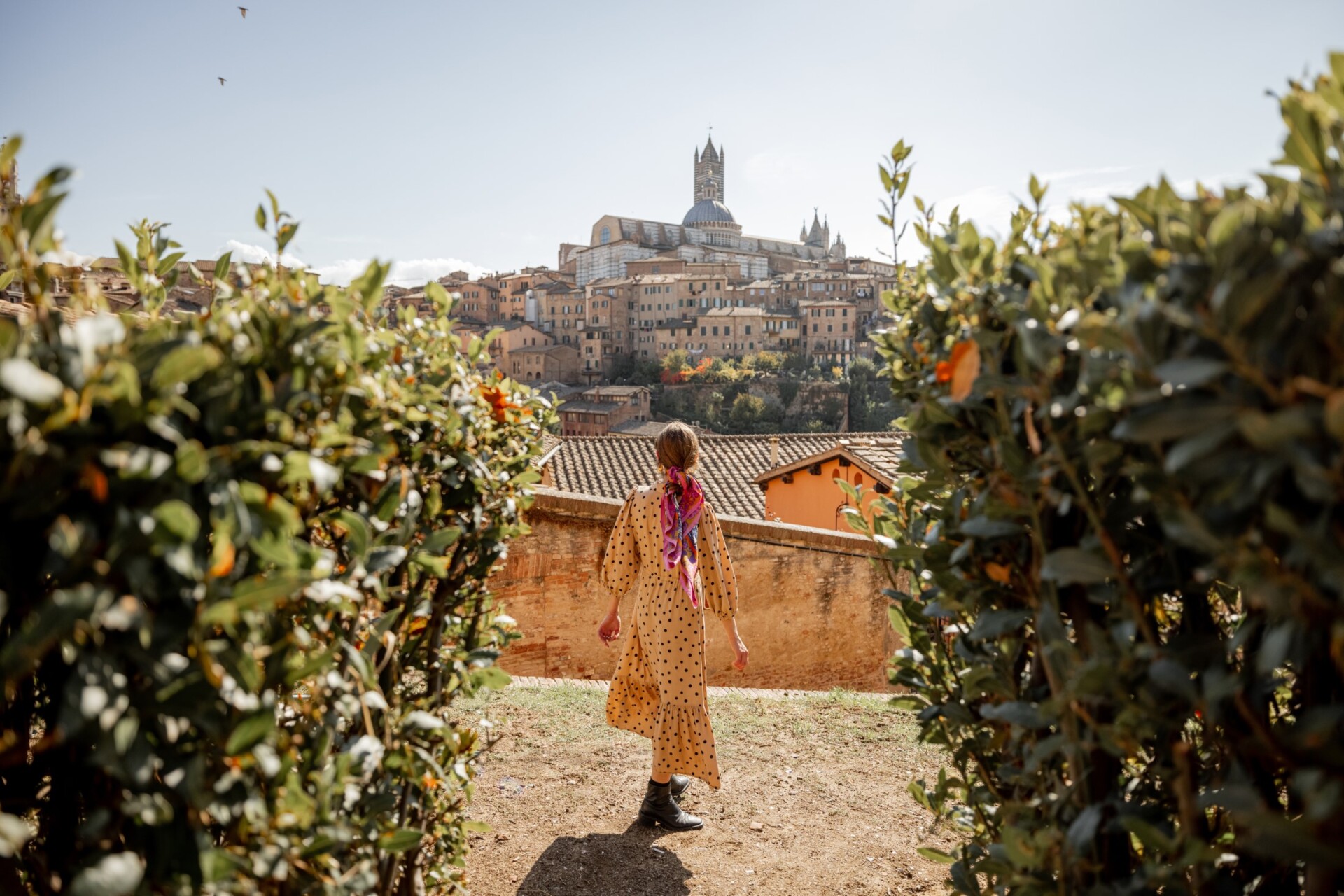 Lucca, Stylish woman walks on background of cityscape of Siena old town. Concept of travel famous cities in Tosacny region of Italy